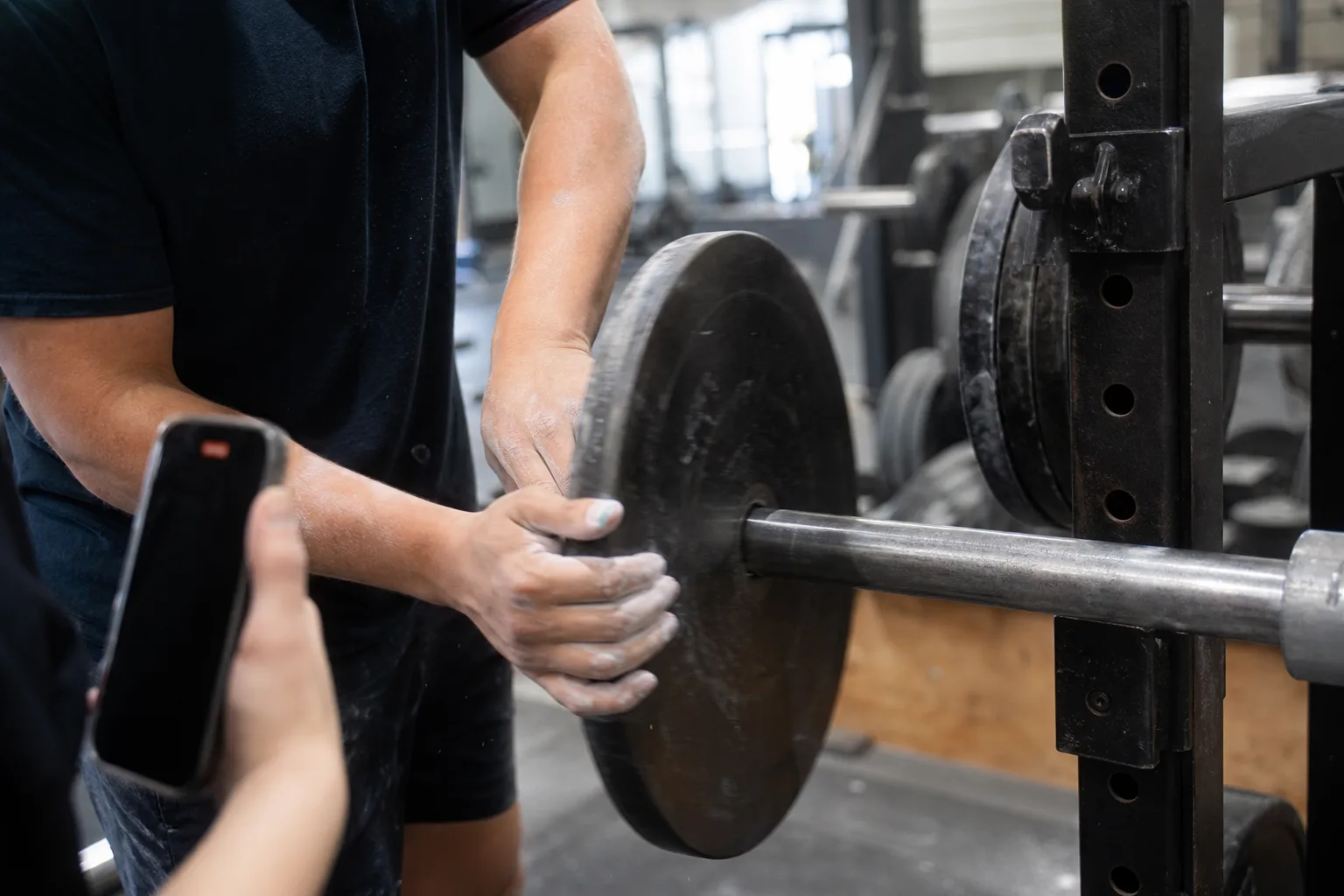 Chalked hands adding a small plate to a barbell